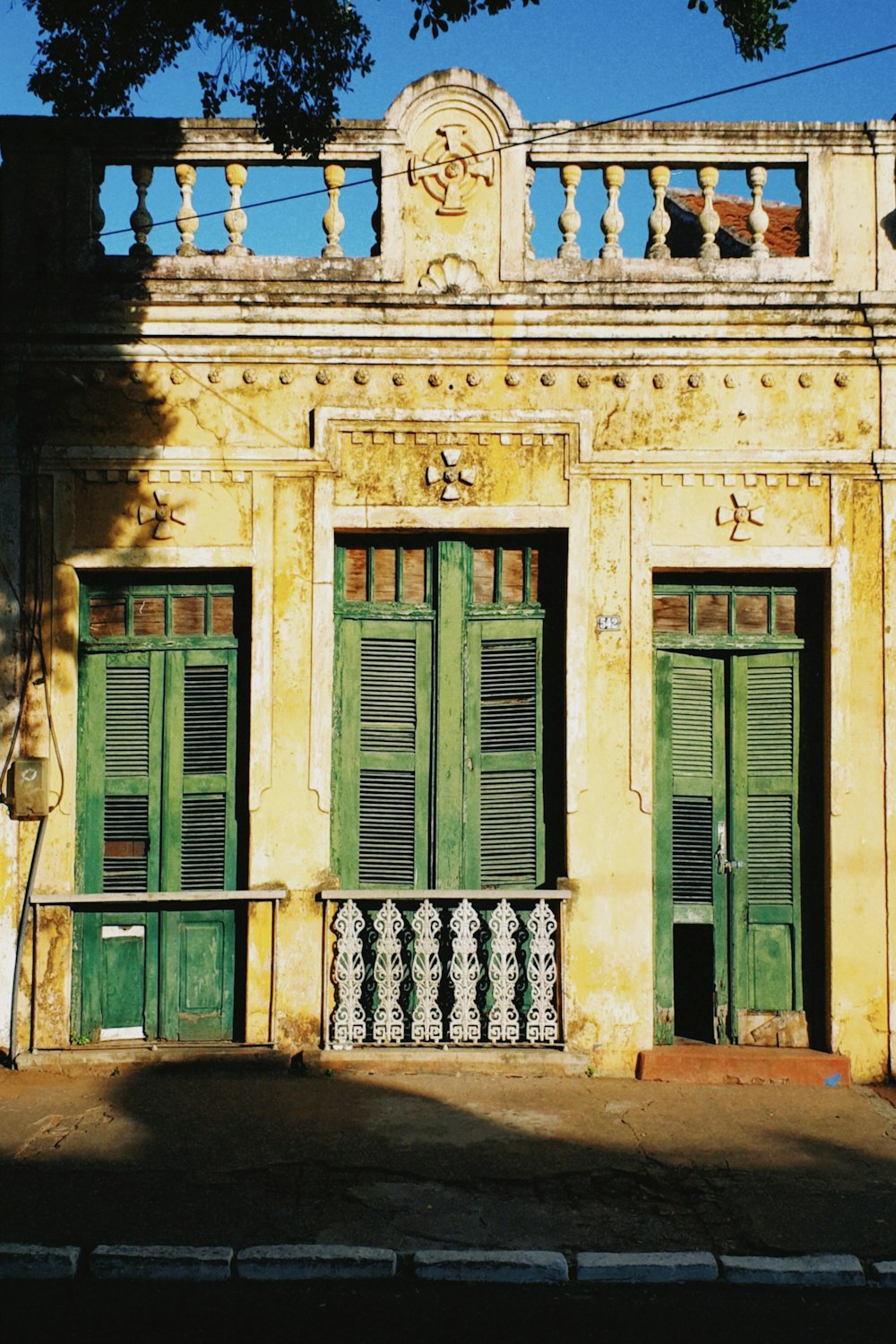 a yellow building with green shutters and a balcony