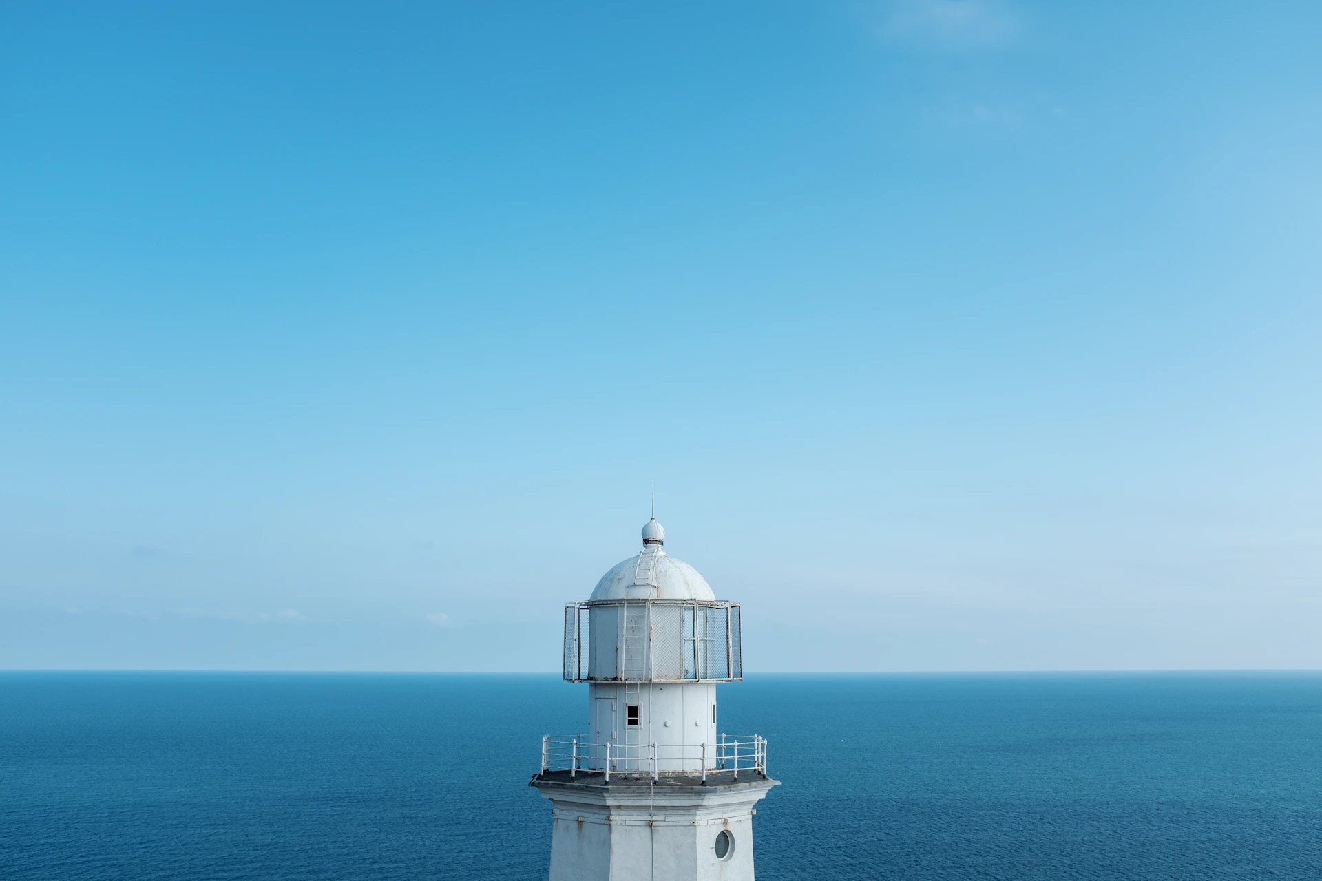a white lighthouse sitting on top of a cliff next to the ocean
