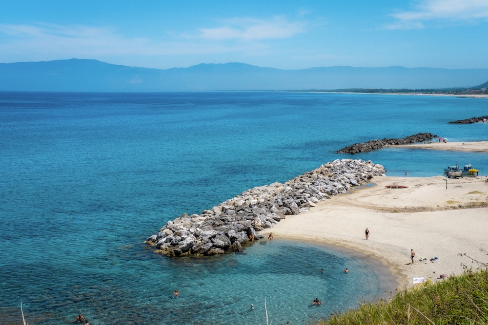 a sandy beach with people swimming in the water