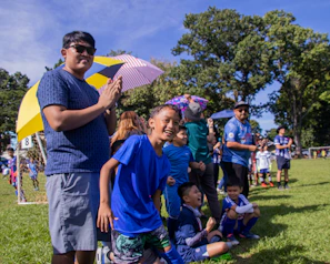 A community sports event hosted by Athleticore, with families cheering and kids trying out different sports activities.