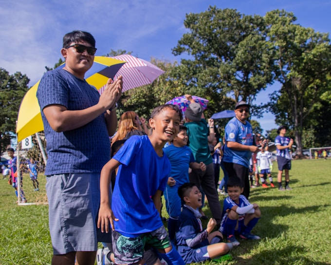 Children playing soccer joyfully on a green field during a community event.