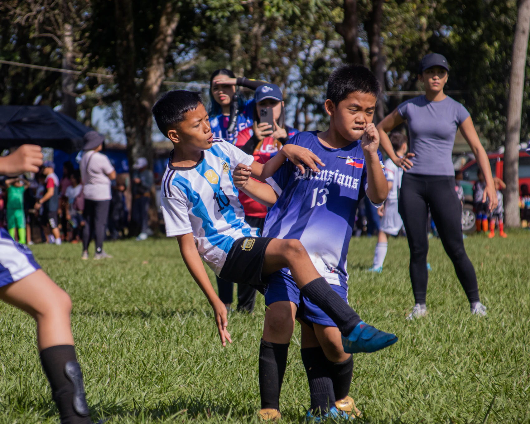 Children playing soccer together on a sunny grass field