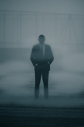 a man in a suit and tie standing in the fog
