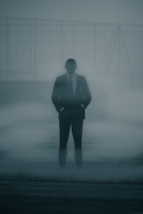 a man in a suit and tie standing in the fog
