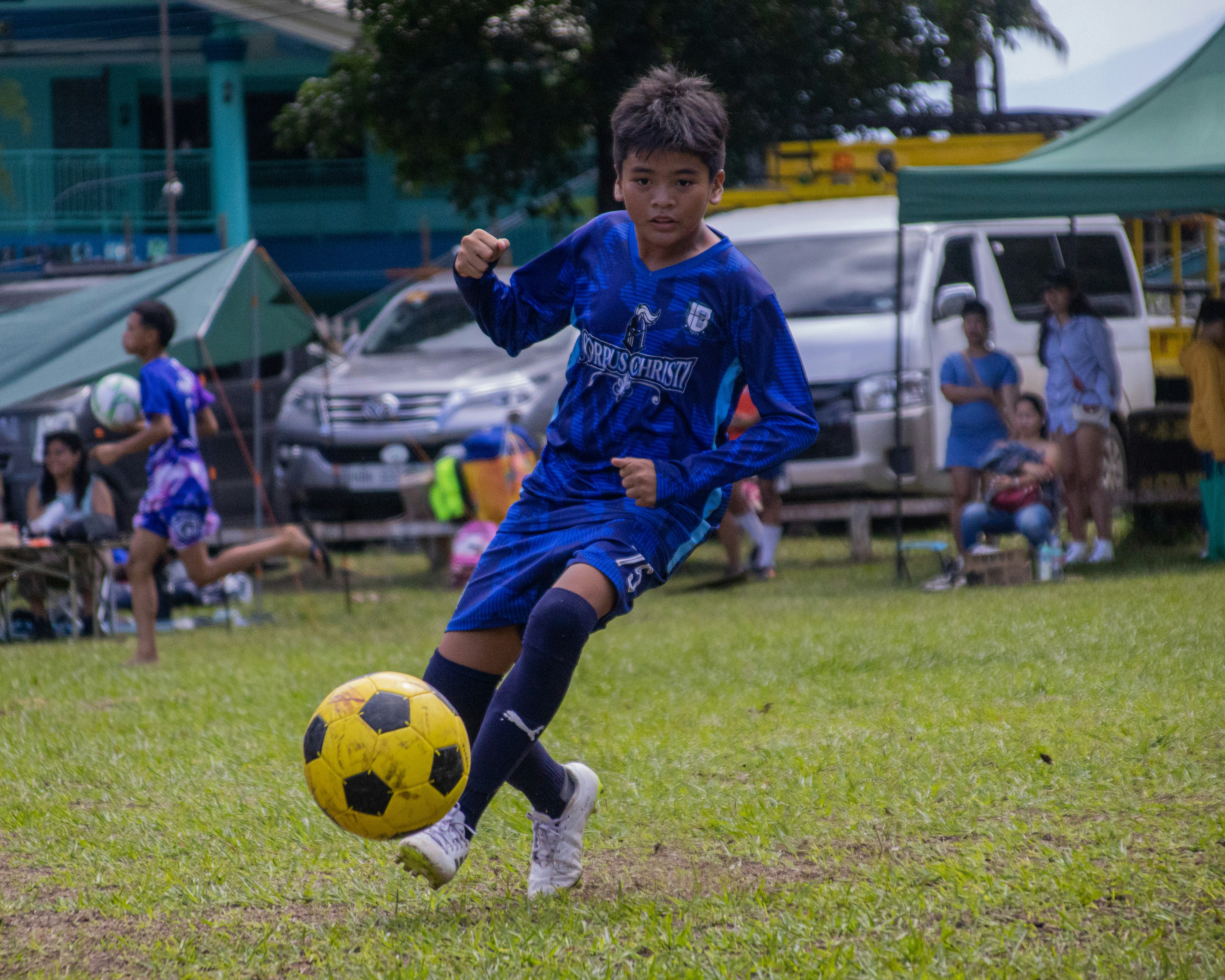 Young boy kicking soccer ball on field