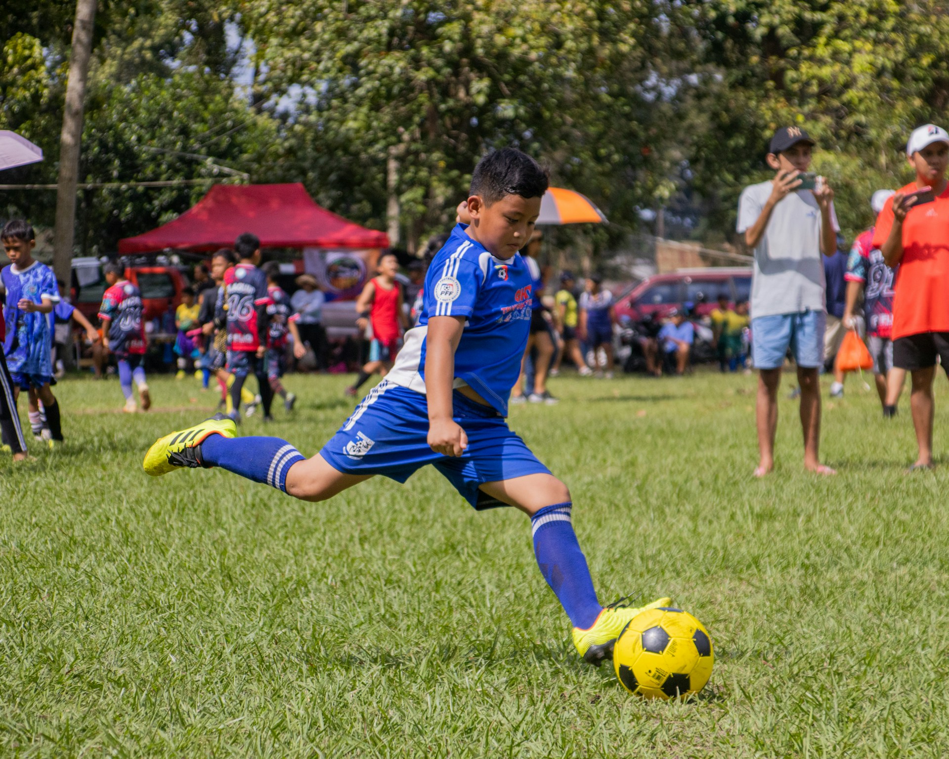 a young boy kicking a soccer ball on a field