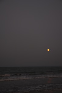 A peaceful moonlit scene with gentle waves and a glowing sage bundle resting nearby.