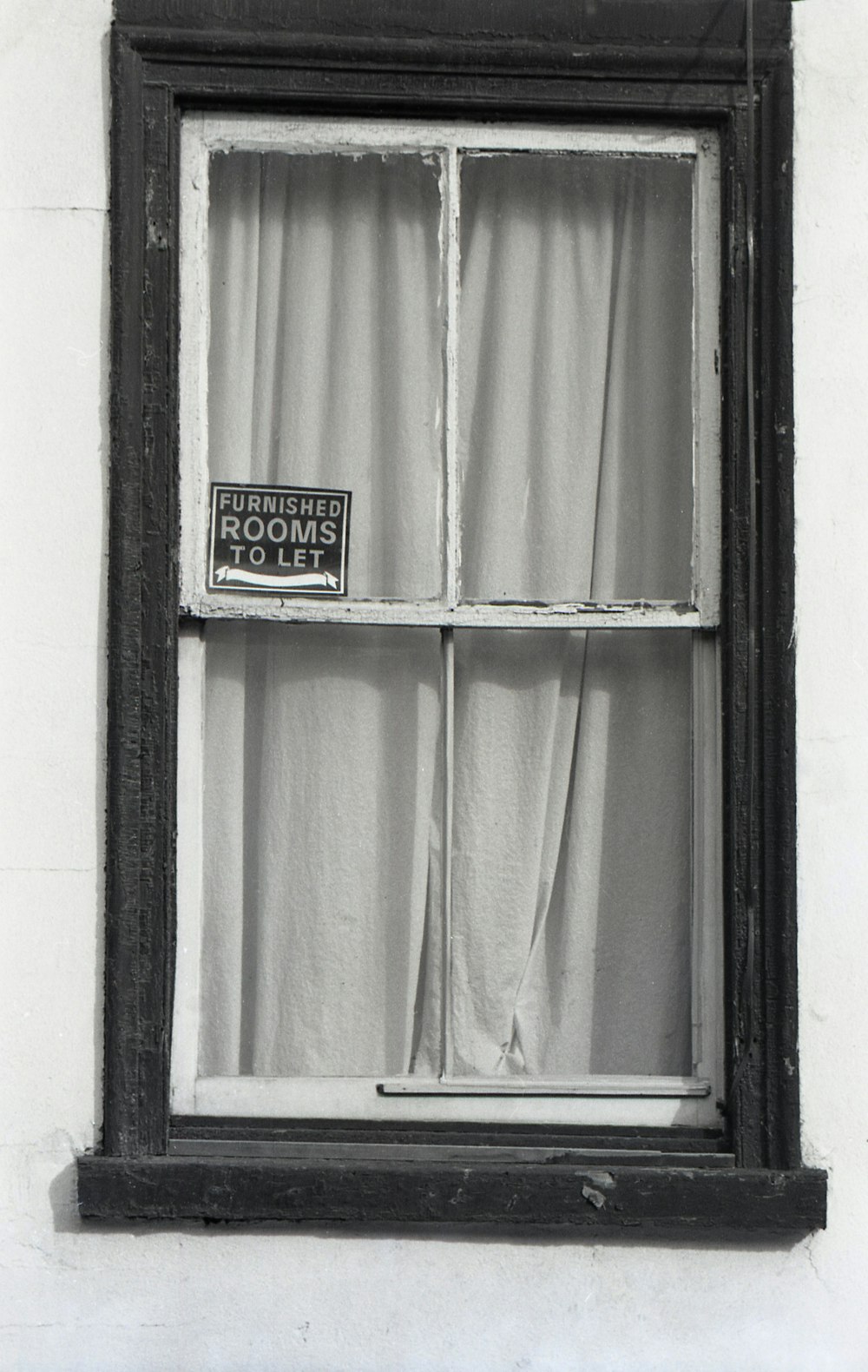 a black and white photo of a window with a sign on it
