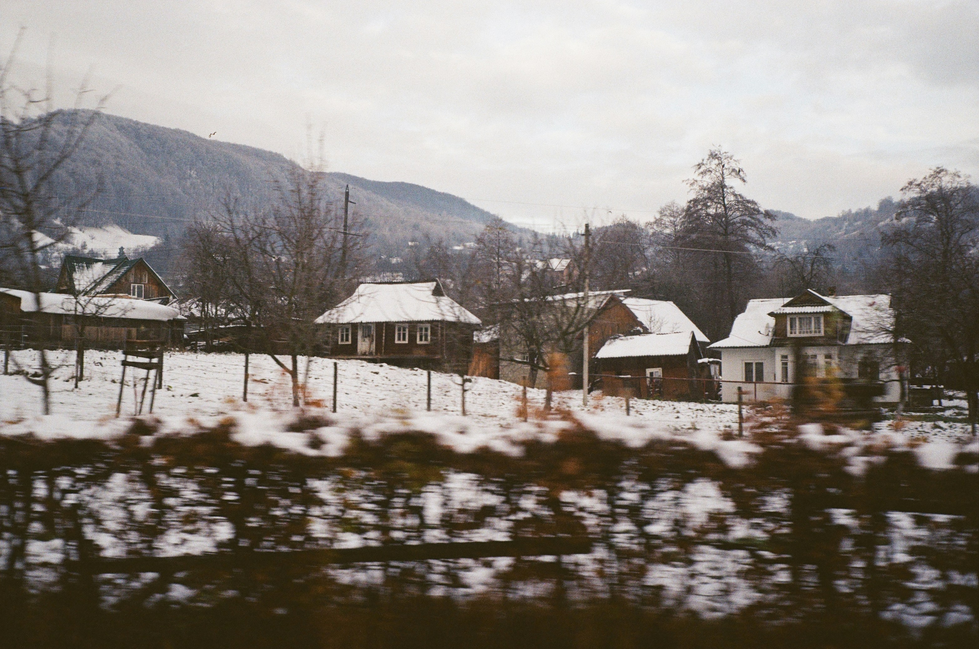 Una vista de un pueblo cubierto de nieve desde un tren en movimiento