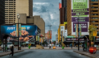 A vibrant city street with prominent real estate advertisements displayed on billboards.