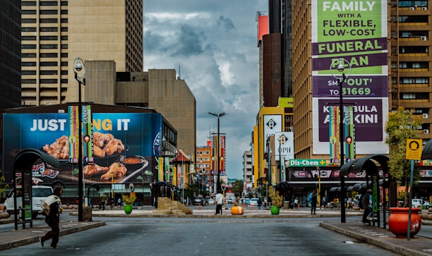 A vibrant city street with prominent real estate advertisements displayed on billboards.