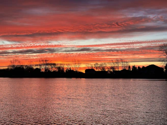 A vibrant sunset over Lake Reschen with colorful village houses reflecting in the water.