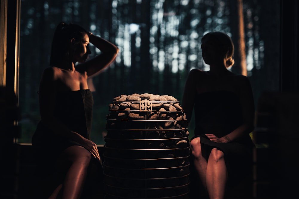 two women sitting next to a stack of stacked plates