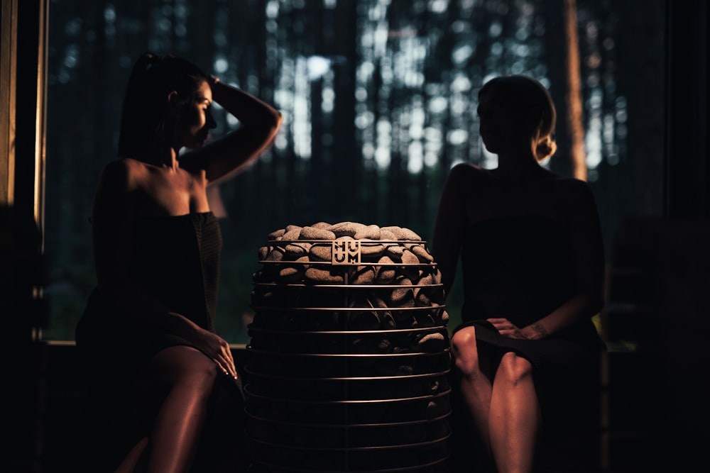 Dos mujeres sentadas junto a una pila de platos apilados