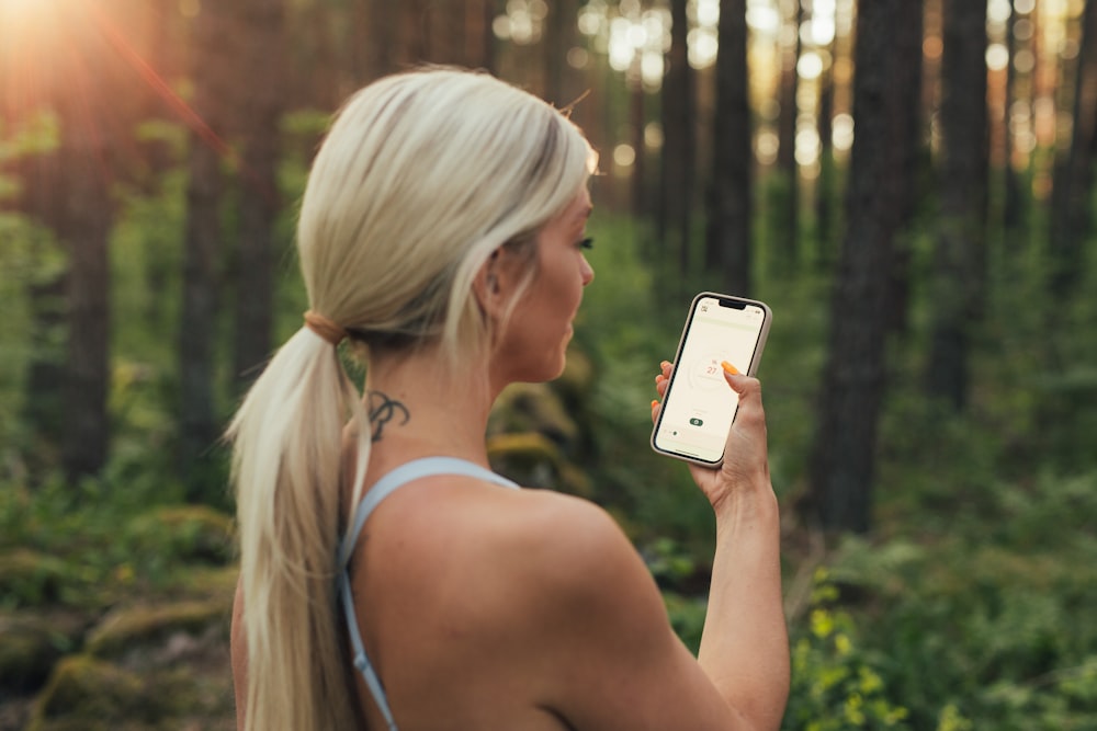 a woman holding a cell phone in a forest