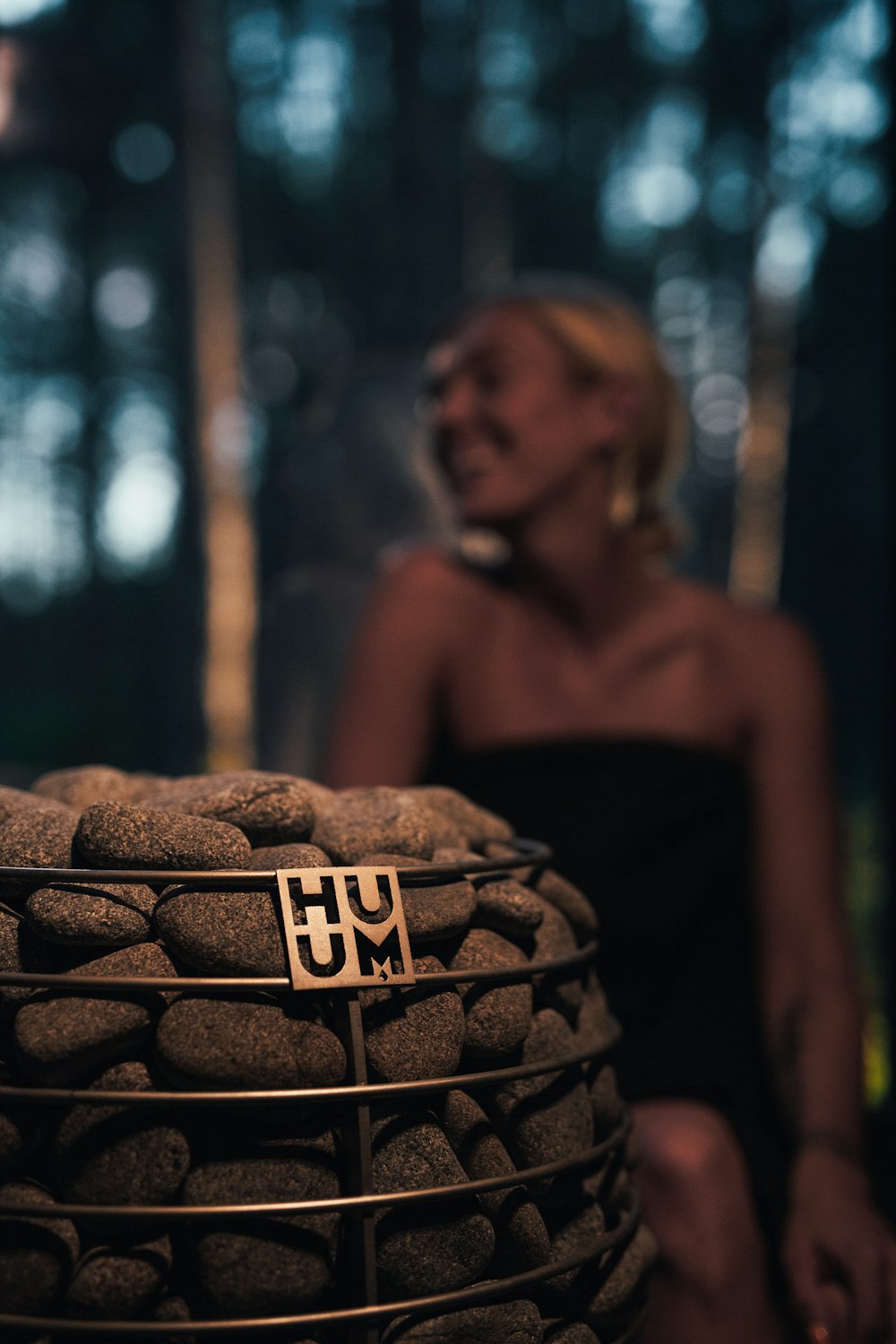 a woman in a black dress sitting next to a basket of rocks