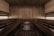 A wooden sauna room with benches lining the walls and a central heating element filled with stones. The warm tones of the wood create a cozy atmosphere, enhanced by soft lighting.