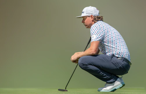 A golfer testing the stretch and comfort of pinline co. trousers on the green.