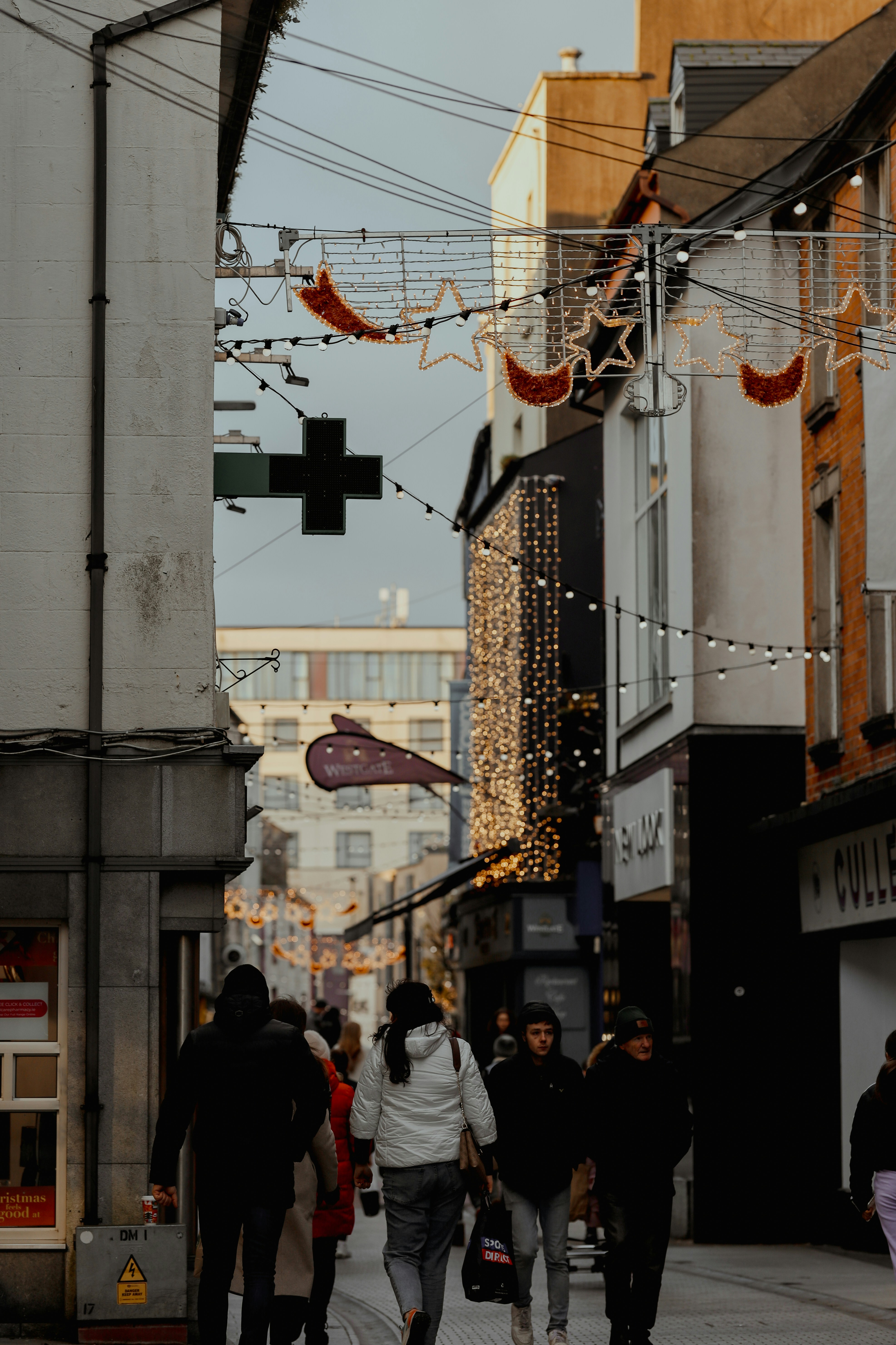 a group of people walking down a street next to tall buildings