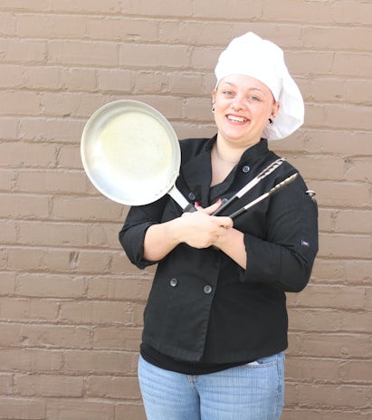 a woman wearing a chef's hat and holding a frying pan
