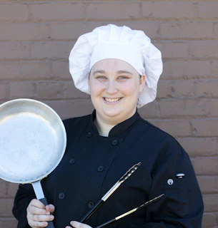 a woman in a chef's outfit holding a frying pan