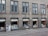 A row of windows on an urban building with a small bookstore at the ground level. The shop displays a variety of books and promotional material in the windows under the sign 'Bøger & Kuriosa'. Above the shop, there are several identical windows on a gray facade.