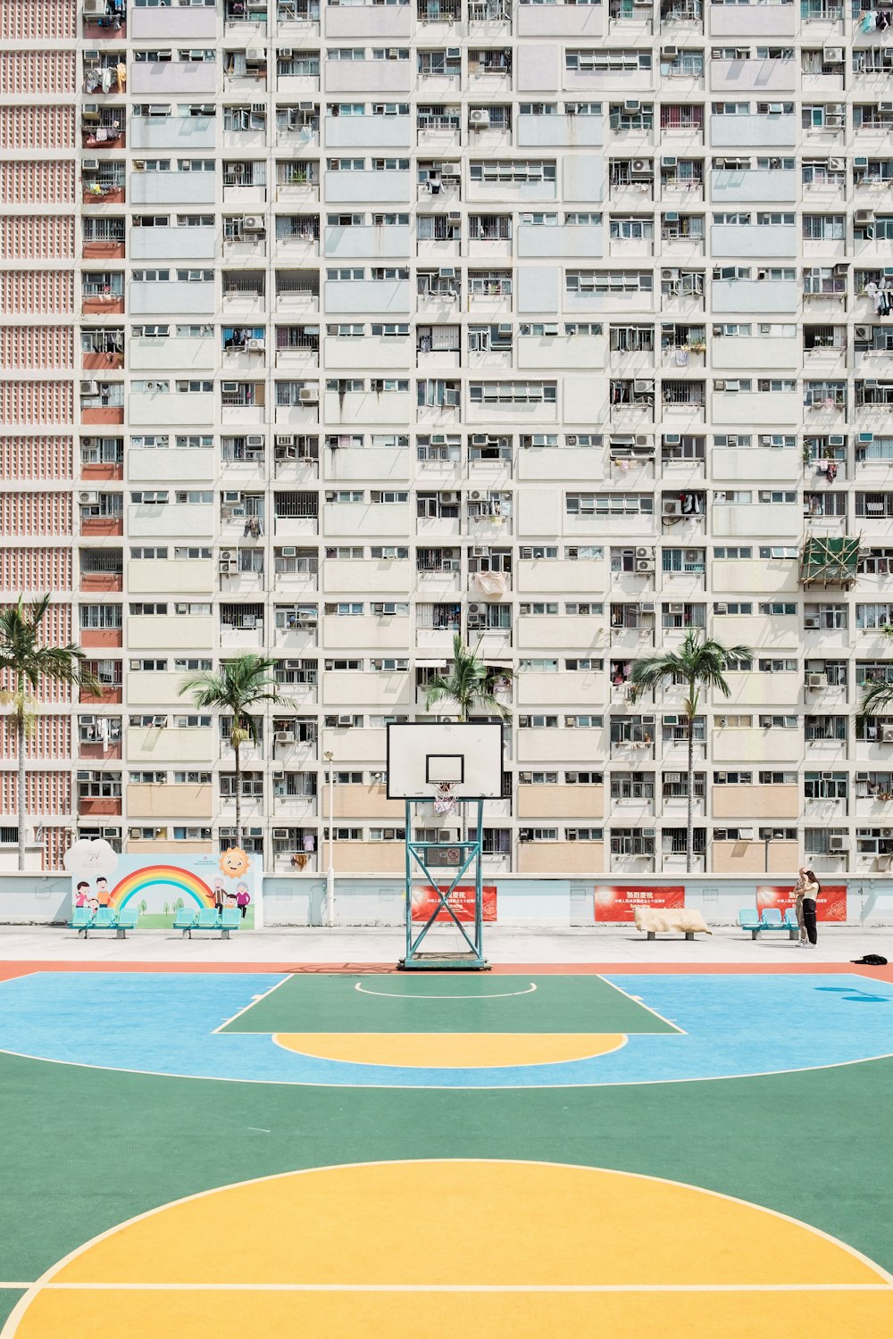 a basketball court in front of a large apartment building