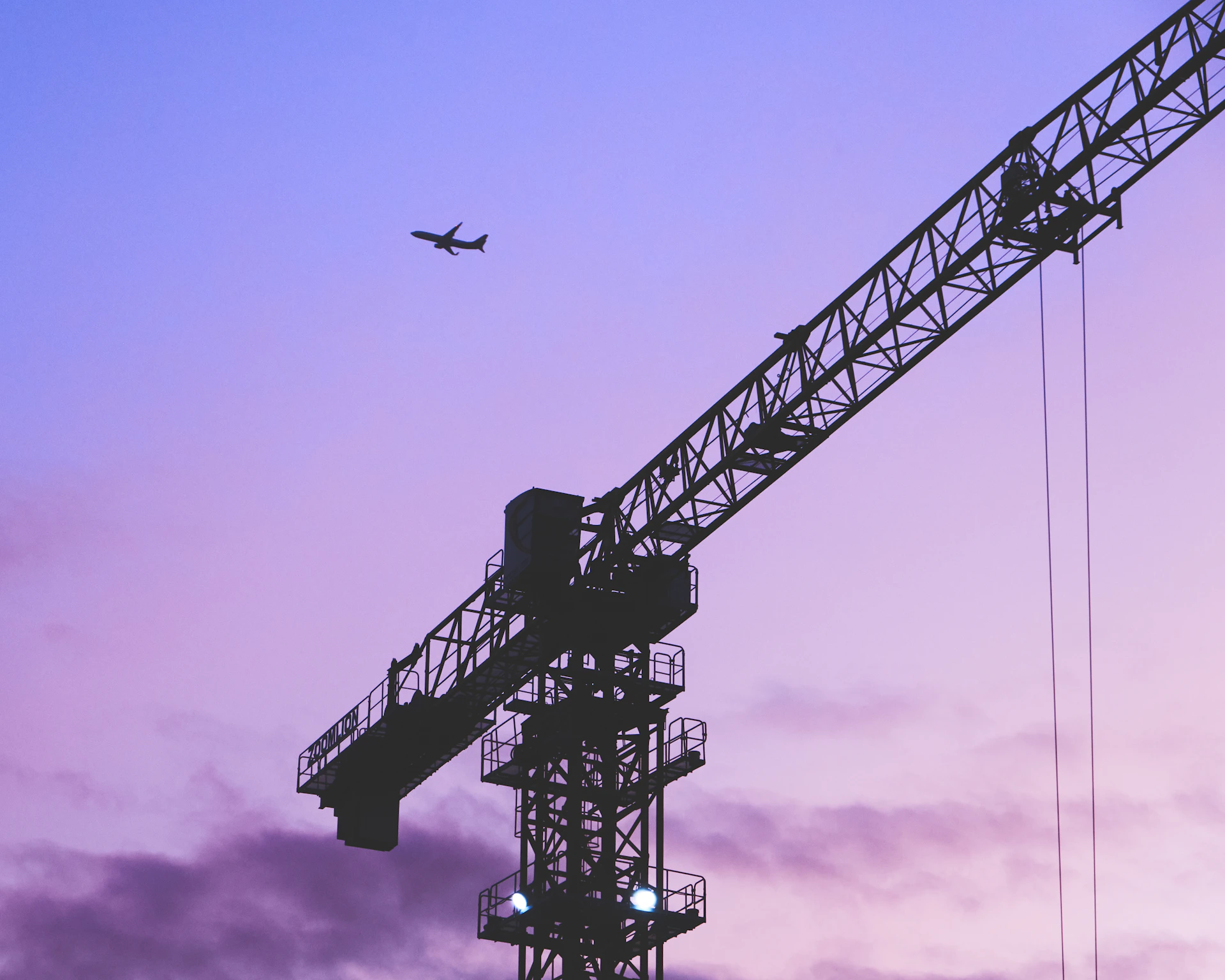 a plane flying over a tall tower under a purple sky