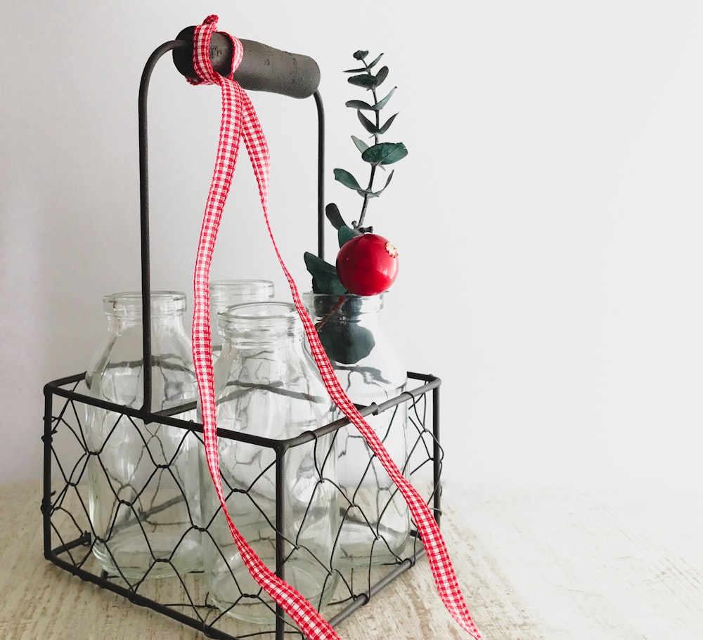 a wire basket with jars and a red ribbon