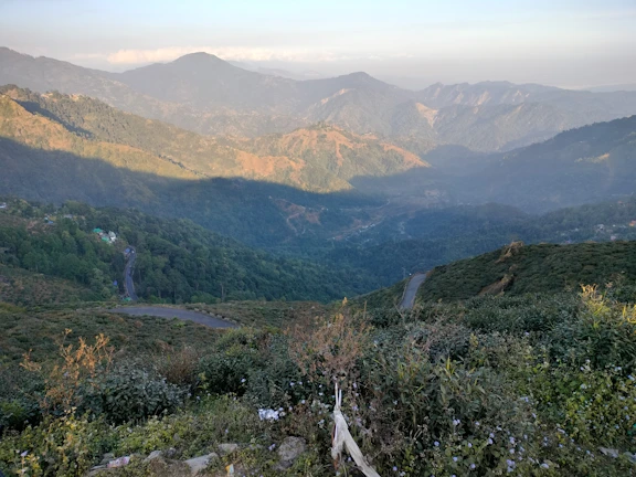 A panoramic view from the air showing winding mountain trails and lush green valleys.