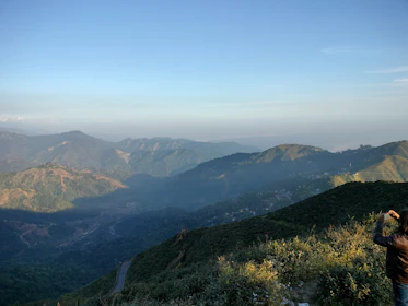 A panoramic view of a mountainous region with a film crew preparing for a shoot.