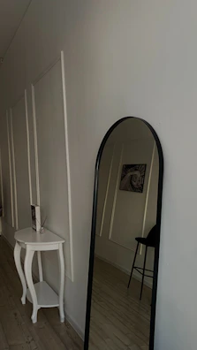 An inviting entryway featuring minimalist decor paired with elegant vintage lighting and a statement mirror.