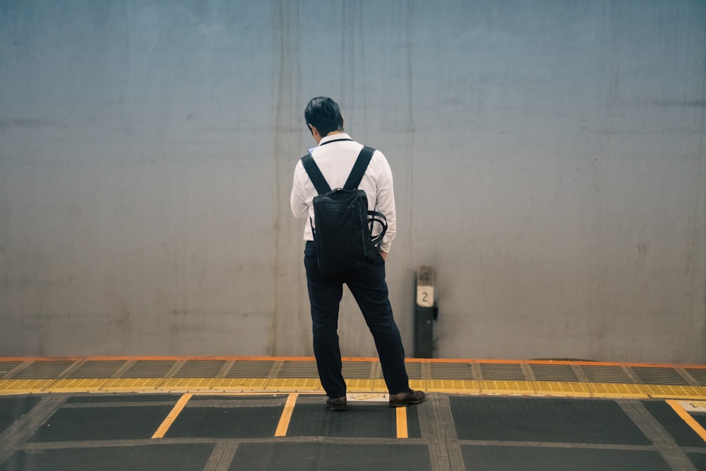 a man standing in a parking lot with a backpack on his back