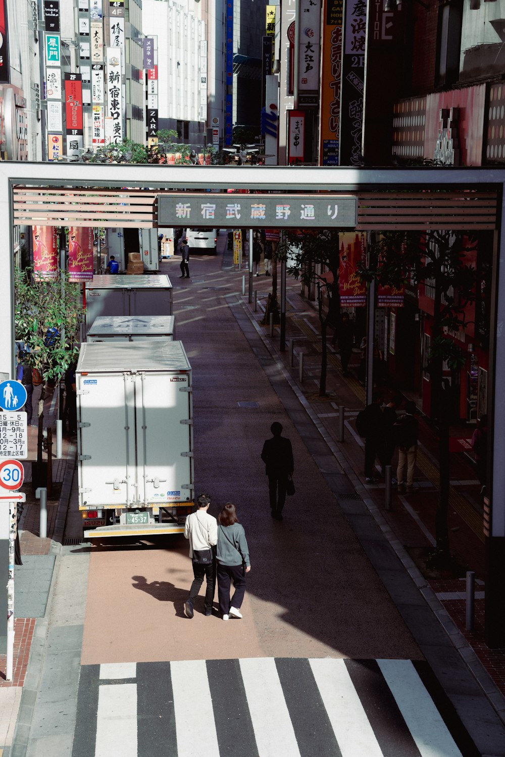 a couple of people walking down a street next to a truck