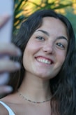 a woman is smiling and holding a cell phone
