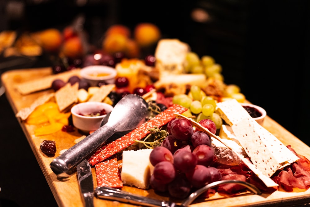 a wooden cutting board topped with lots of different types of cheese