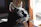 Picture of a cheerful man with a sleek black cat sitting on his lap near a window.