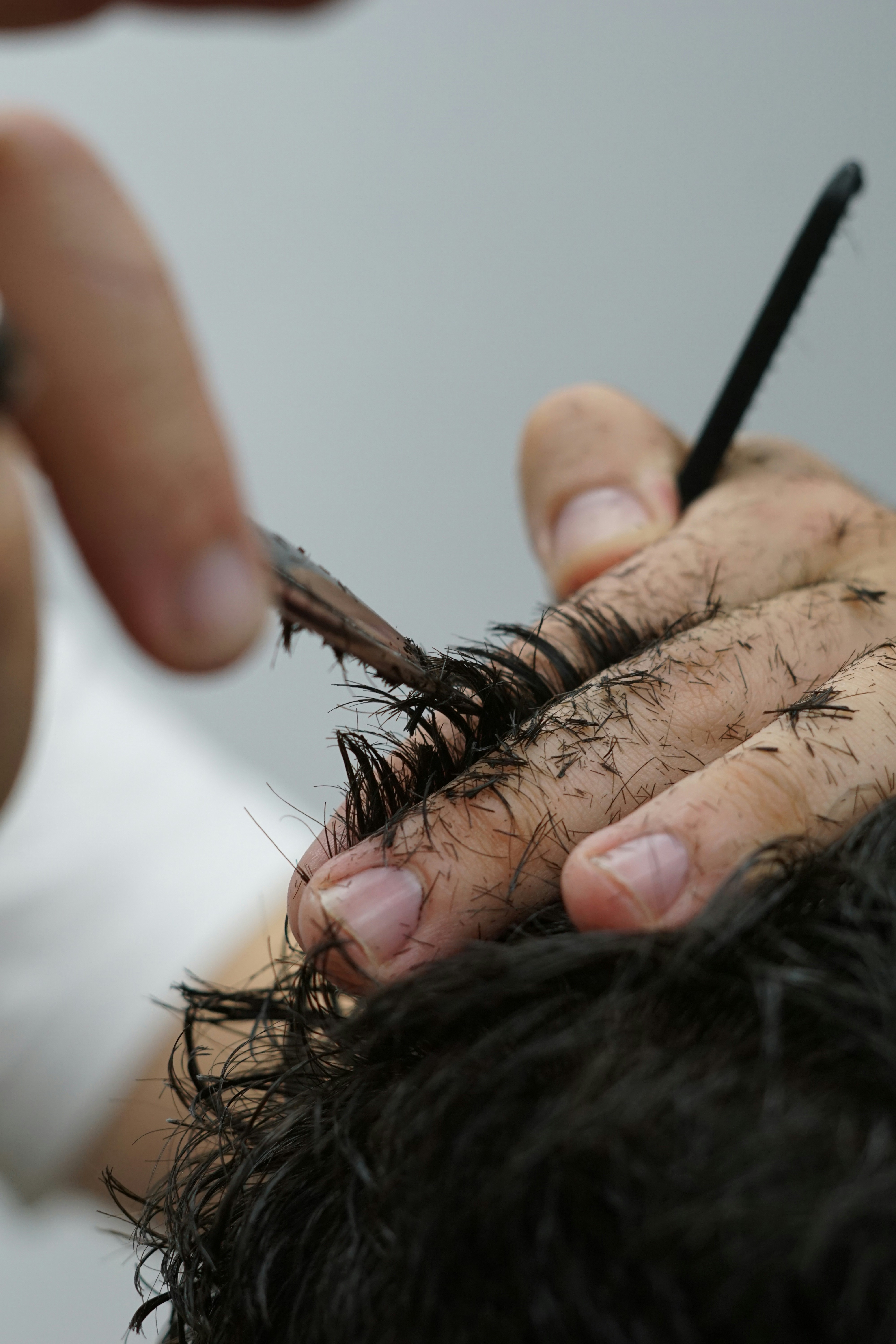 a person cutting another persons hair with a pair of scissors