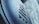 Close-up of a textured surface with an embossed logo in a modern font, set against a blurred backdrop that combines light blue and gray hues.