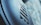 Close-up of a textured surface with an embossed logo in a modern font, set against a blurred backdrop that combines light blue and gray hues.