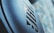 Close-up of a textured surface with an embossed logo in a modern font, set against a blurred backdrop that combines light blue and gray hues.