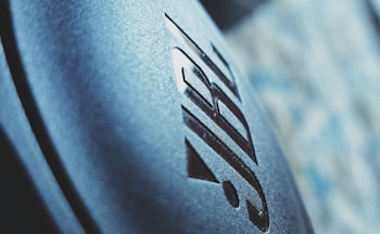 Close-up of a textured surface with an embossed logo in a modern font, set against a blurred backdrop that combines light blue and gray hues.