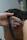 A close-up of a person getting a haircut. The hands of the barber are visible, one holding a comb and the other a straight razor. The dark, wet hair is being carefully trimmed, with small pieces of hair scattered on the barber's hand.