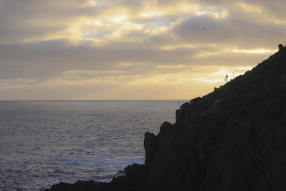 a group of people standing on top of a cliff next to the ocean