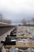Close-up of a railway grounding clamp being installed by a professional wearing protective equipment.