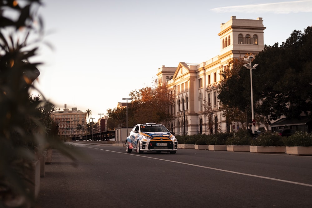 a white car driving down a street next to tall buildings