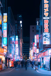 a busy city street at night with neon signs