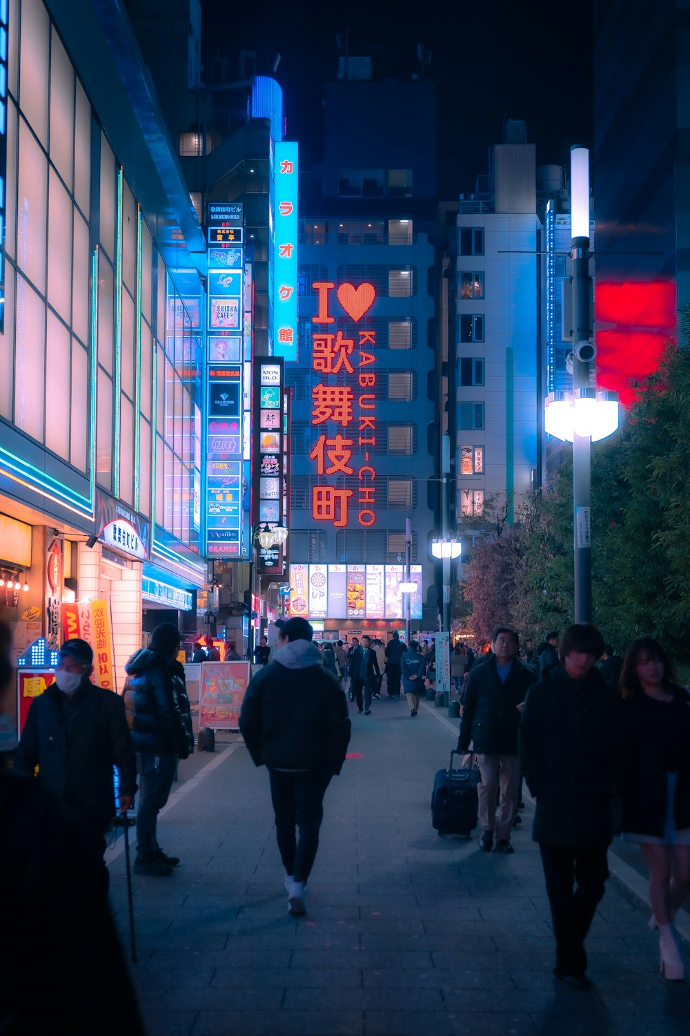 a group of people walking down a street at night