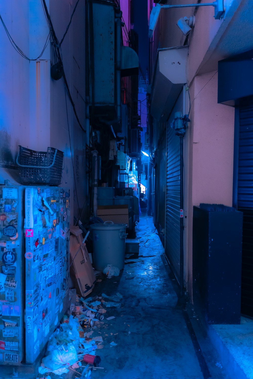 a narrow alleyway with a trash can and a garbage can