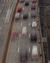 A highway filled with cars captured in motion, creating a blurred effect. The vehicles are traveling on a multi-lane road, with red taillights trailing due to the movement. A speed limit sign on the right side indicates a limit of 40 miles per hour.
